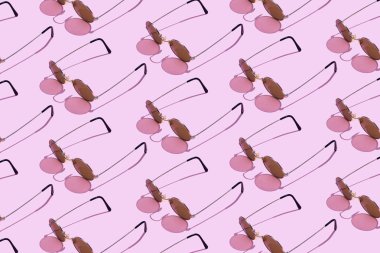 Pembe arka plan üzerinde düzenlenen yuvarlak güneş gözlüğü