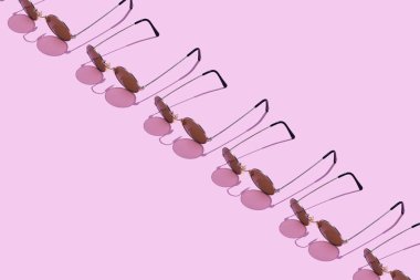 Pembe arka plan üzerinde düzenlenen yuvarlak güneş gözlüğü