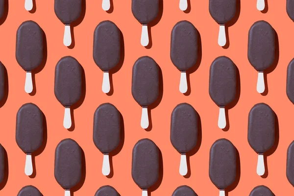 Ice cream popsicles organized in a row over coral background