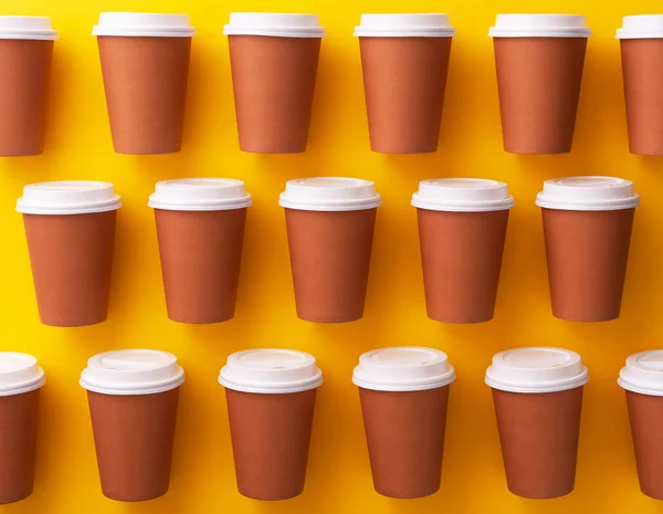 Multiple disposable coffee cups organized over yellow background