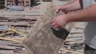 İnşaat alanında bir adam elindeki tahtayı büker.
