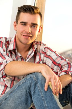 Pencere kenarında oturan çekici bir adam.