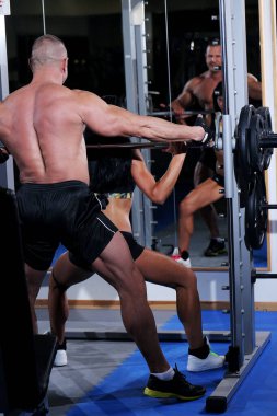 Güzel, kaslı bir çift spor salonunda birlikte çalışıyor.