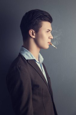Yakışıklı, sigara içen ciddi bir adam.