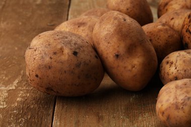 Ahşap masalarda kabuğu soyulmamış taze patates.