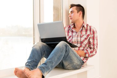 Pencere kenarında oturan çekici bir adam.