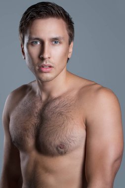 Açık mavi bir arkaplanda çıplak poz veren yakışıklı bir adamın portresi.