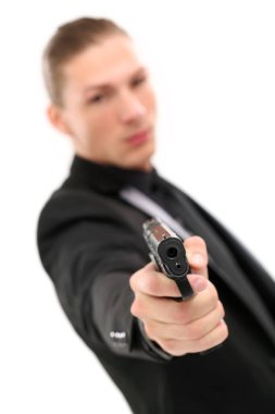 Siyah takım elbiseli yakışıklı bir adam ve beyaz arka planda duran bir tabanca.