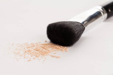 Beyaz arka planda bej tozuyla doğal makyaj fırçası