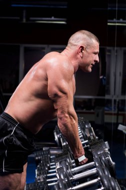 Yakışıklı kaslı adam spor salonunda çalışıyor.