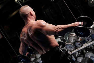 Yakışıklı kaslı adam spor salonunda çalışıyor ve poz veriyor.