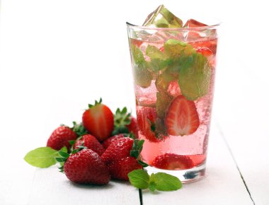 Beyaz ahşap bir masada taze çilek ve naneli mojito.