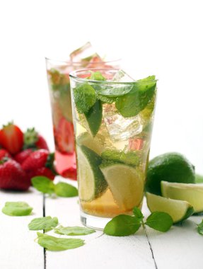 Beyaz ahşap bir masada taze çilek ve naneli mojito.