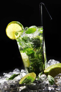 Taze su, yeşil nane ve siyah arka planda limon.