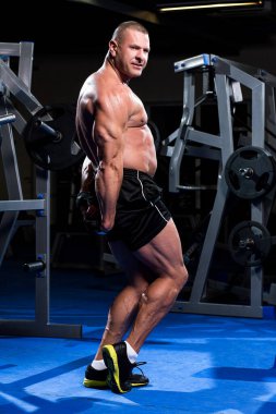 Yakışıklı kaslı adam spor salonunda çalışıyor.