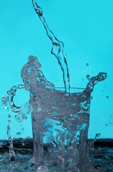 Υγρό Που Χύνεται Στο Ποτήρι Πάνω Από Μπλε Φόντο — Φωτογραφία Αρχείου