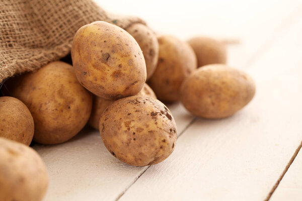 Rustic fresh unpeeled potatoes on a white wooden table 