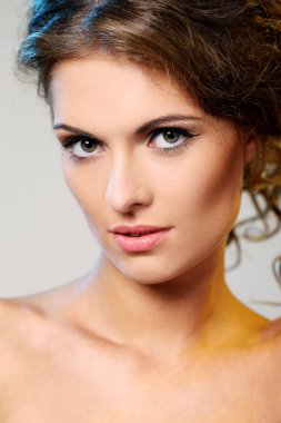 kıvırcık saçlı ve hafif bir arka plan üzerinde poz çıplak omuzlarına güzel esmer bir kadın portresi