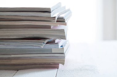 Beyaz bir masada renkli dergiler yığını