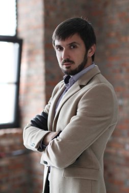 Palto giyen yakışıklı adamın stüdyo portresi.