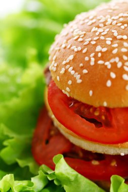 Salata yapraklarının üzerinde büyük ve lezzetli bir burger.