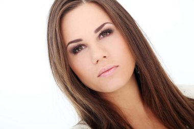 Kahverengi saçlı güzel kız beyaz arka planda poz veriyor.