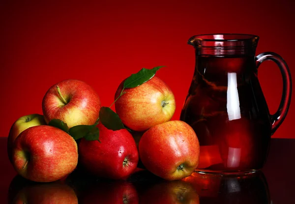 Jabłka Dzban Sokiem Czerwonym Tle — Zdjęcie stockowe