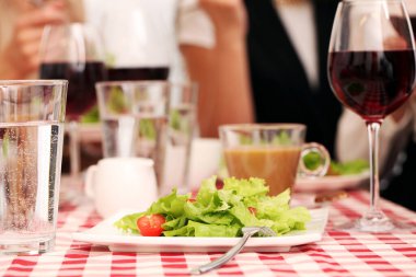 Sağlıklı salata ve kırmızı şarap bir restoranda kare masa örtüsü üzerinde.