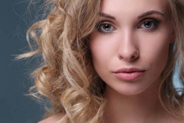 Mavi arka planda kıvırcık saçlı güzel bir kadın.