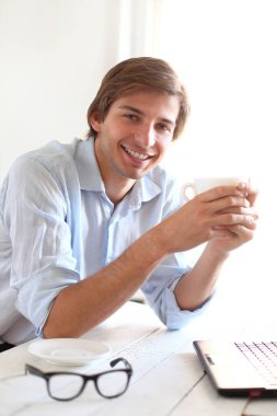 Ofiste poz veren mavi gömlekli yakışıklı bir genç.