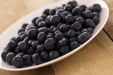 Ahşap bir yüzey üzerinde bir tabak yaban mersini