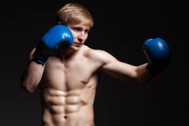 Siyah arka planda mavi eldivenli yakışıklı bir boksör.