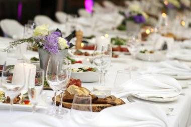 Bir kutlamada, içinde çiçekler ve bir sürü farklı yiyecek olan büyük bir yemek masası.