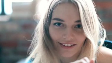 Evdeki yatakta kameraya poz veren bir kadın. 