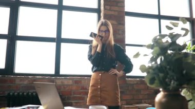 İş kadını ofiste akıllı telefondan konuşuyor.
