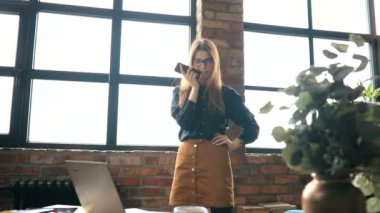 İş kadını ofiste akıllı telefondan konuşuyor.