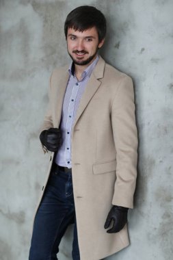 Palto giyen yakışıklı adamın stüdyo portresi.