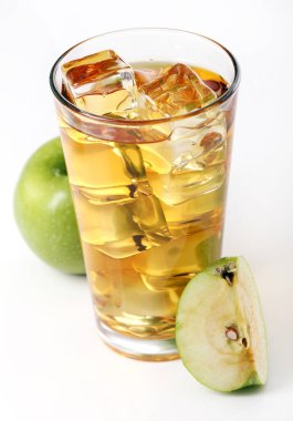 Bir bardak buzlu elma suyu ve beyaz arka planda duran elmalar.