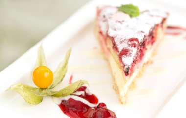 Lezzetli katmanlı meyveli kek ve beyaz tabakta diğer meyveler.