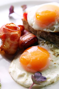 Çırpılmış yumurta, domuz pastırması ve yeşil bir tabakta servis edilir.