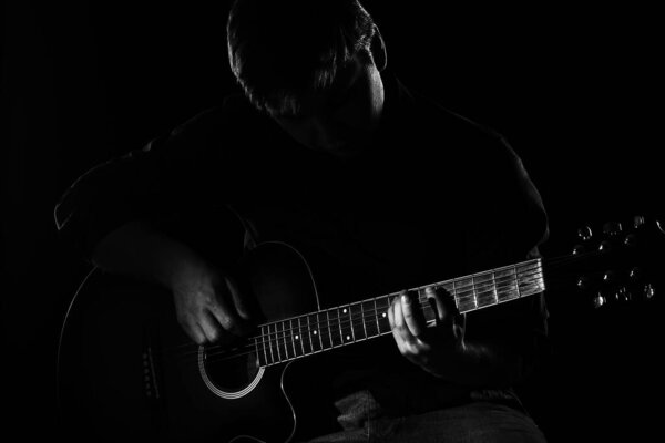 Man with guitar in the darkness