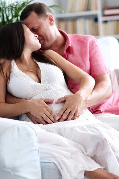 怀孕了可爱的夫妻坐在沙发上 — 图库照片