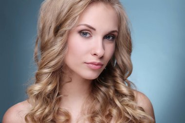 Mavi arka planda kıvırcık saçlı güzel bir kadın.