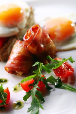 Çırpılmış yumurta, domuz pastırması ve yeşil bir tabakta servis edilir.