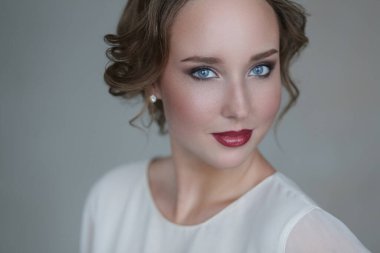 Gri arka planda makyajlı hoş bir genç kadın.