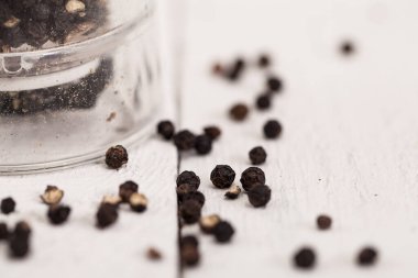 Beyaz bir masanın üzerinde cam değirmenli karabiber.