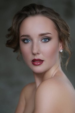 Gri arka planda makyajlı hoş bir genç kadın.