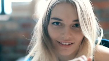 Evdeki yatakta kameraya poz veren bir kadın. 