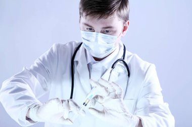 Doktor elinde şırınga tutuyor.