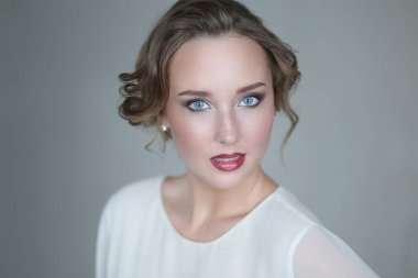 Gri arka planda makyajlı hoş bir genç kadın.